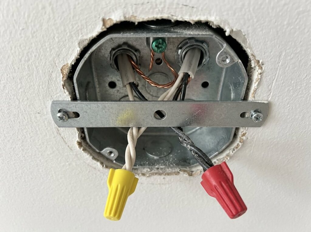 Ceiling box with a mounting bracket, ground on the green screw and wire nut connections for a light fixture