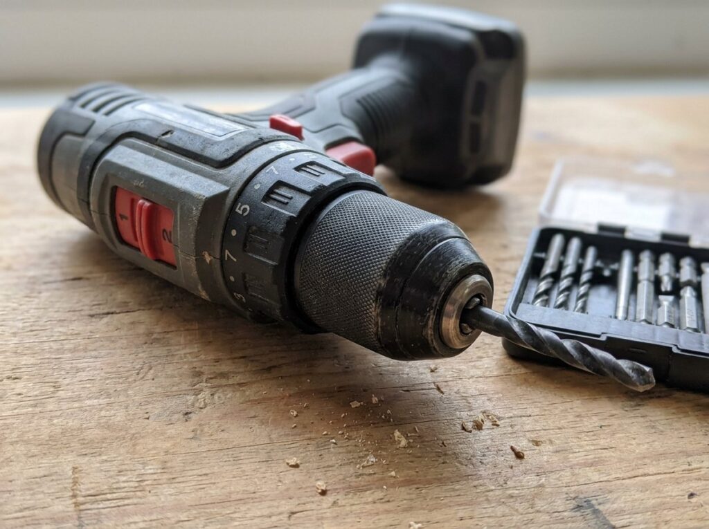 Close-up of a cordless drill chuck holding a bit with the clutch collar and speed switch visible
